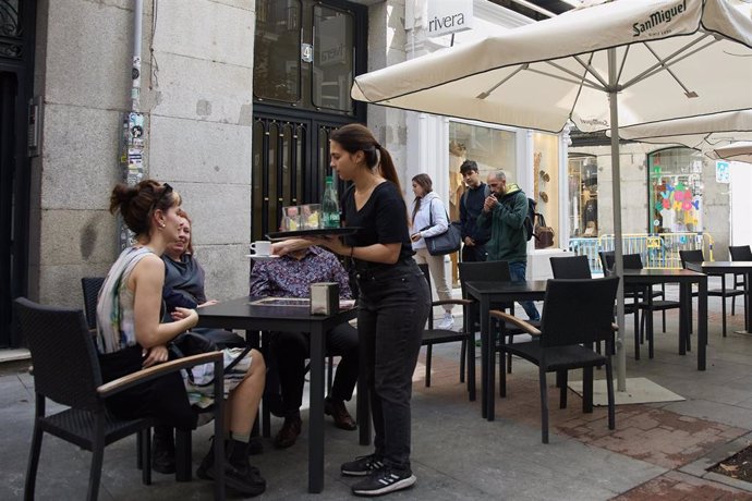 Archivo - Una camarera atendiendo las mesas de un bar