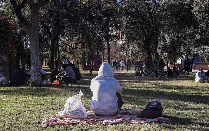 Archivo - Varias personas comen durante un reparto de alimentos a personas sin recursos, en Valencia.