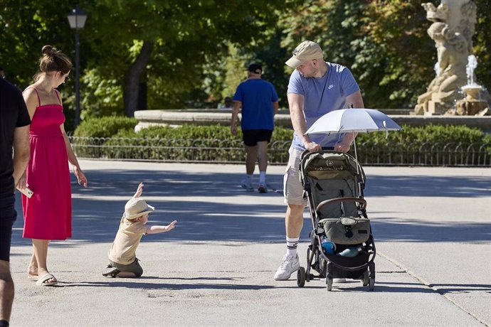 Archivo - Varias personas pasean con un carrito de bebé en el parque de El Retiro.