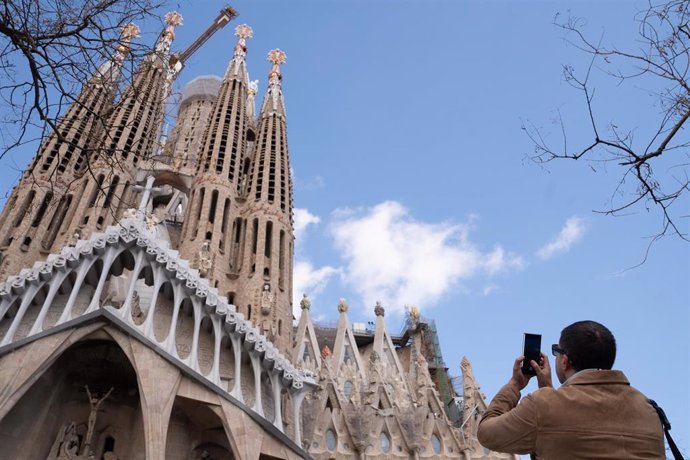 Archivo - Un turista saca una foto junto a la Sagrada Familia, en marzo de 2024, en Barcelona (Catalunya)