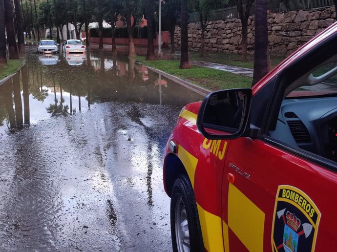 Un vehículo de Bomberos ante dos coches atrapados en un embalsamiento debido a las fuertes lluvias caidas en Benalmádena