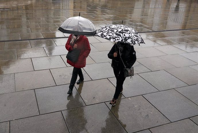 Archivo - Dos personas se refugian con un paraguas de la lluvia en Vitoria, País Vasco (España), a 19 de marzo de 2021.