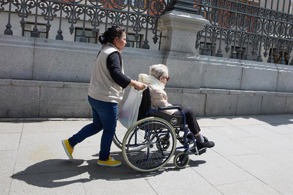 Archivo - Una mujer mayor en silla de ruedas y su cuidadora pasean por el centro de la ciudad, a 4 de junio de 2023, en Madrid (España).