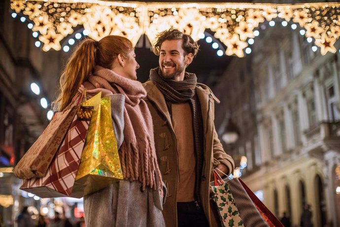 Archivo - Pareja joven paseando por un centro comercial en Navidad