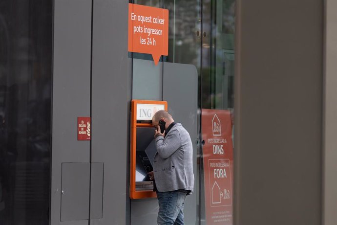 Un hombre saca dinero de un cajero automático del banco ING