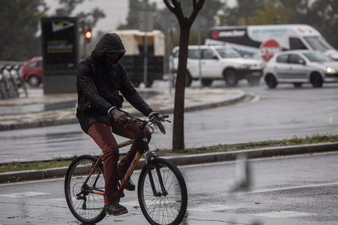 Archivo - Un hombre circula en bicicleta bajo la lluvia. Imagen de archivo. 