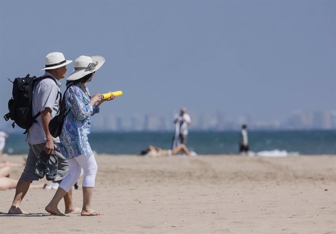 Archivo - Varias personas caminan por la playa.