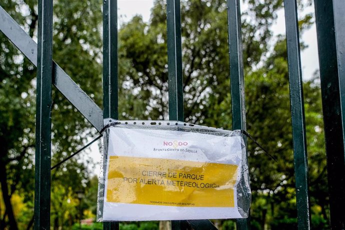 Archivo - Cartel en una reja de entrada al Parque de María Luisa que indica el cierre por alerta meteorológica. Imagen de archivo.