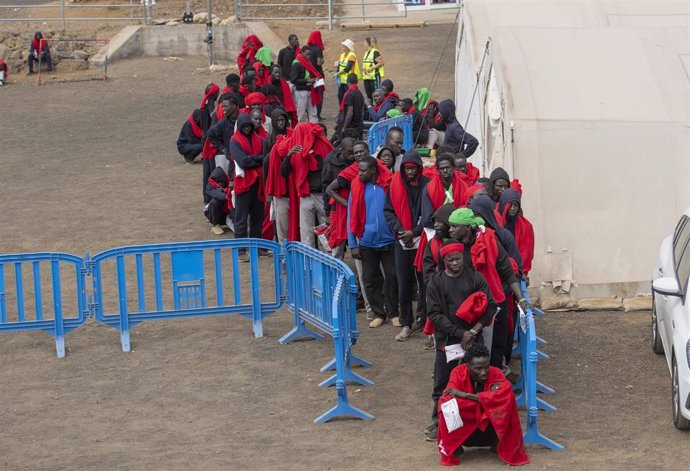 Archivo - Varios migrantes esperan para ser trasladados al puerto de La Estaca