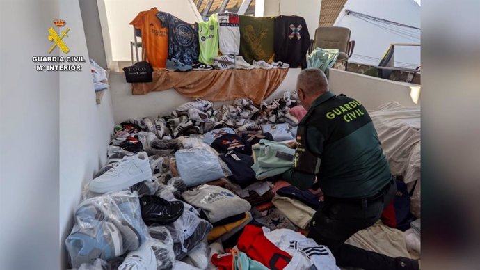 Un agente de la Guardia Civil junto a las prendas falsificadas intervenidas.