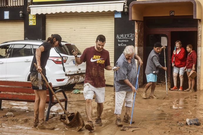 Varias personas realizan labores de limpieza tras el paso de la DANA por el barrio de La Torre de Valencia