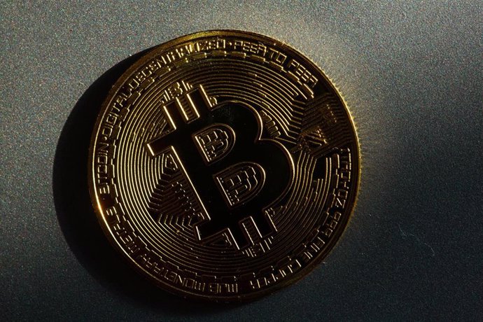 Archivo - FILED - 05 March 2022, Berlin: A coin bearing the logo of the bitcoin cryptocurrency lies on a table. 