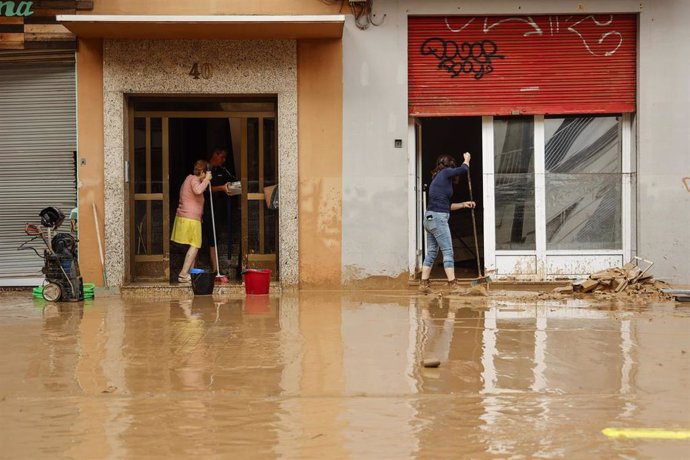 Varias personas realizan labores de limpieza tras el paso de la DANA por el barrio de La Torre