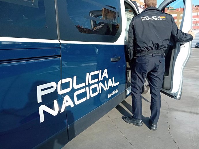 Un agente y un coche de la Policía Nacional.