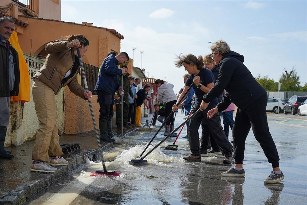 Varios vecinos de la calle Buen Pastor, de San Fernando, barren el agua a la alcantarilla, a 31 de octubre de 2024, en Cádiz (Andalucía, España).