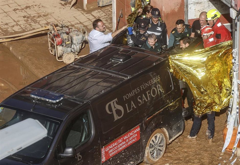 Un furgón de la funeraria sale de un garaje con cadáveres localizados tras el paso de la DANA, en la pedanía de la Torre, en Valncia