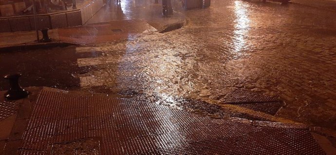 Archivo - Una pequeña balsa de agua generada por la lluvia en una calle de Huelva, en una imagen de archivo.