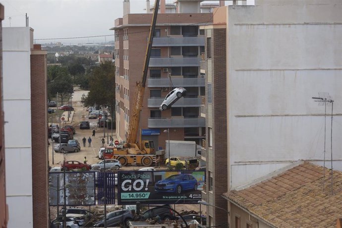 Vista de una grúa retirando coches tras el paso de la DANA en el barrio de la Torre