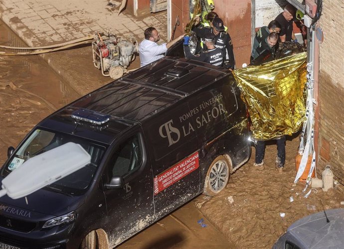 Un furgón de la funeraria sale de un garaje con cadáveres localizados tras el paso de la DANA