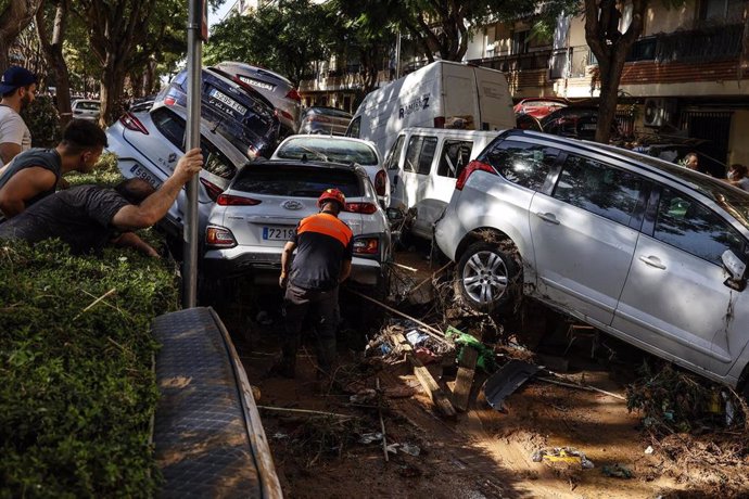 Varias personas tratan de mover los coches amontonados, a 2 de noviembre de 2024, en Alfafar, Valencia, Comunidad Valenciana (España). 