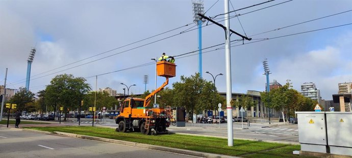 Dos operarios reparan la catenaria frente al estadio de La Romareda este domingo tras producirse una avería en la línea del tranvía.