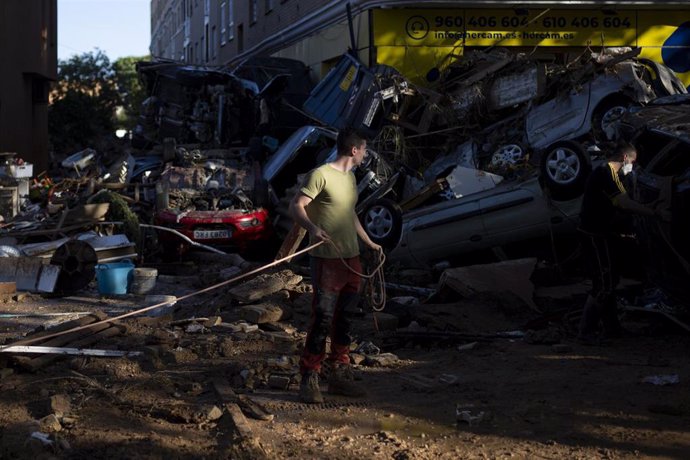 Varios personas tratan de quitar coches amontonados, a 2 de noviembre de 2024, en Alfafar, Valencia