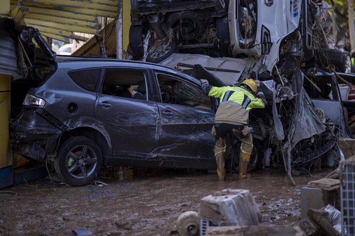 Varios bomberos buscan a personas entre coches, en Alfafar, Valencia