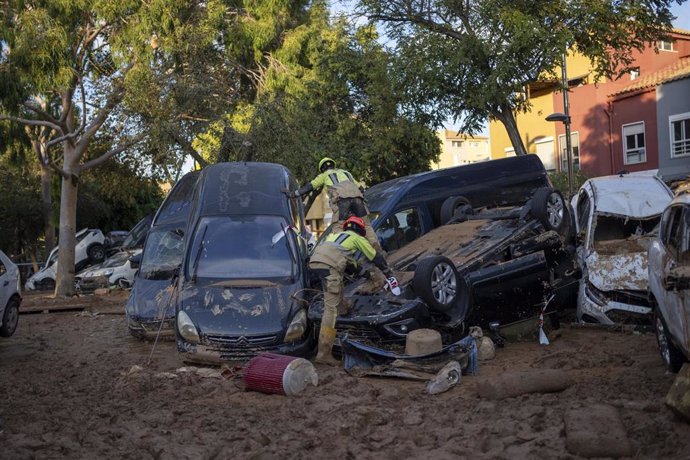 Varios bomberos buscan a personas entre coches en Alfafar, Valencia, tras el paso de la DANA el 29 de octubre.