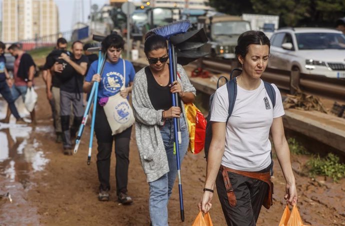 Varias personas con bolsas tras el paso de la DANA, en el barrio de La Torre