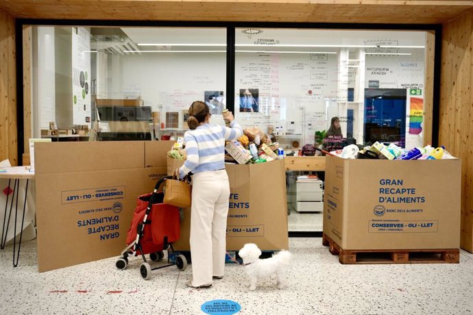 Una dona donando menjar a la Biblioteca Montserrat Abelló a través la campanya conjunta entre l'Ajuntament de Barcelona i Banc d'Aliments.