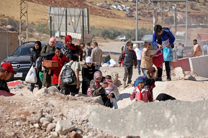 MASNAA BORDER CROSSING, Oct. 12, 2024  -- This photo shows displaced people from Lebanon crossing a hole on the road caused by an Israeli airstrike near the Masnaa Border Crossing, Lebanon, on Oct. 11, 2024. About a week ago, Israeli airstrike hit the Syr