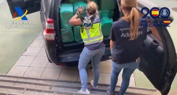 Dos agentes de Policía y Aduanas cargan la cocaína incautada en Algeciras en un furgón.