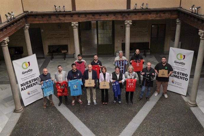 Los diputados provinciales magdalena Rodríguez y Óscar Moral (en el centro), muestran lotes de Alimentos de Segovia junto a representantes de los clubes deportivos, con sus camisetas con el logo de la marca.