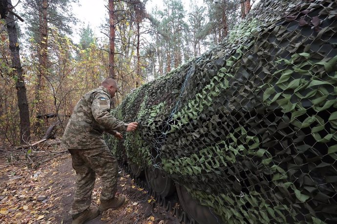 Un militar ucraniano junto a capacidades militares cubiertas con camuflaje