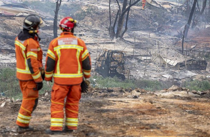 Archivo - Bomberos trabajando en un incendio en un asentamiento de Palos de la Frontera en febrero de 2021. 