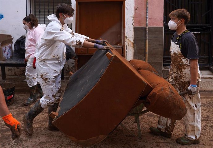 Dos jóvenes retiran un sofá inutilizable tras el paso de la DANA en Aldaia (Valencia).