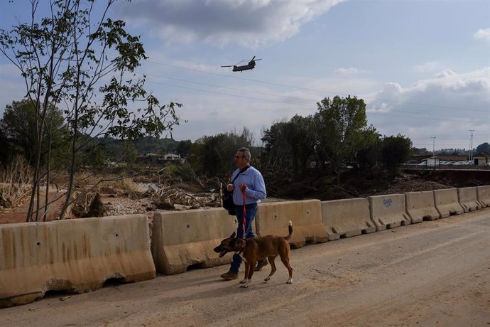 Un hombre con un perro en la entrada de Pedralba, municipio de Valencia afectado por la DANA.