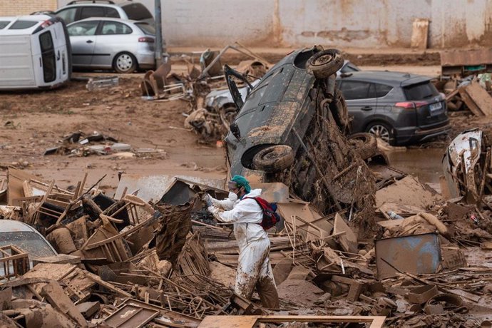 Un hombre con un EPI realiza tareas de limpieza tras el paso de la DANA en Alfafar, junto a un vehículo volcado, a 9 de noviembre de 2024, en Alfafar, Valencia, Comunidad Valenciana (España). 