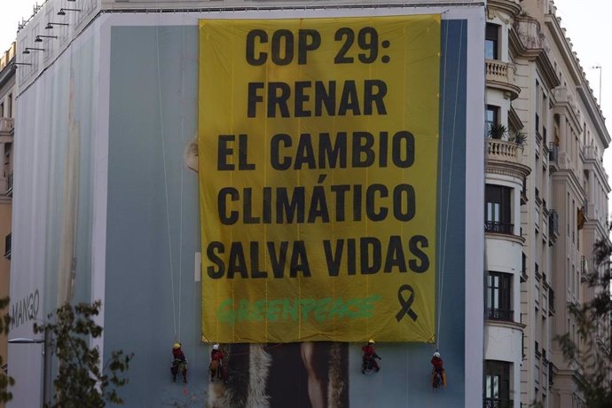 Activistas de Greenpeace despliegan la pancarta en la plaza de España de Madrid.