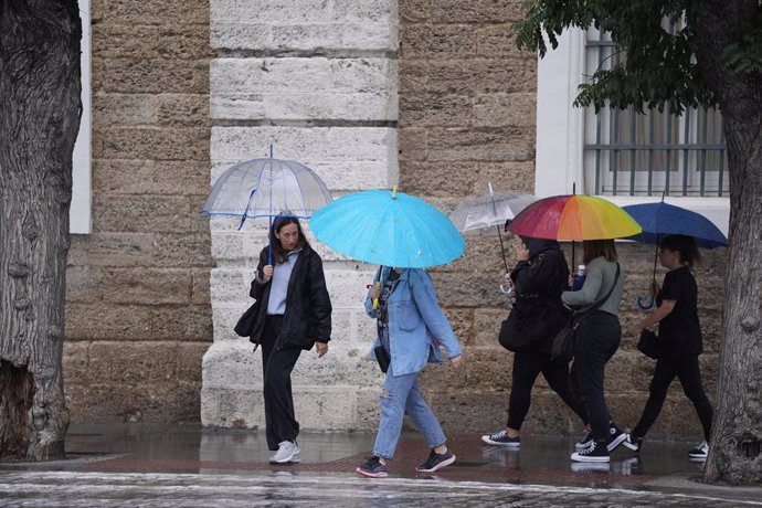 Archivo - Transeuntes bajo sus paraguas durante la intensa lluvia.