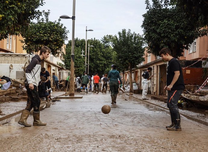 Dos chicos juegan al fútbol en Alfafar, a 8 de noviembre de 2024, en Valencia, Comunidad Valenciana (España). Diez días después de la tragedia, los servicios de emergencia apuran hasta el límite la búsqueda de desaparecidos por la DANA en Valencia. El núm