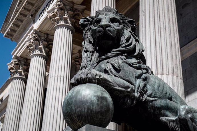 Archivo - Uno de los emblemáticos leones que se encuentran delante de la fachada del Congreso de los Diputados en la Plaza de las Cortes de Madrid.