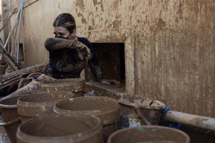 Una mujer se limpia la mascarilla mientras saca agua y barro de un sótano afectado por la DANA, a 10 de noviembre de 2024, en Catarroja, Valencia, Comunidad Valenciana (España).