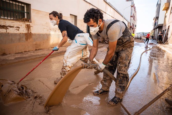 Imatge de dos persones realitzant tasques de neteja en una de les zones afectades per la DANA, a la localitat valenciana de Massanassa.   