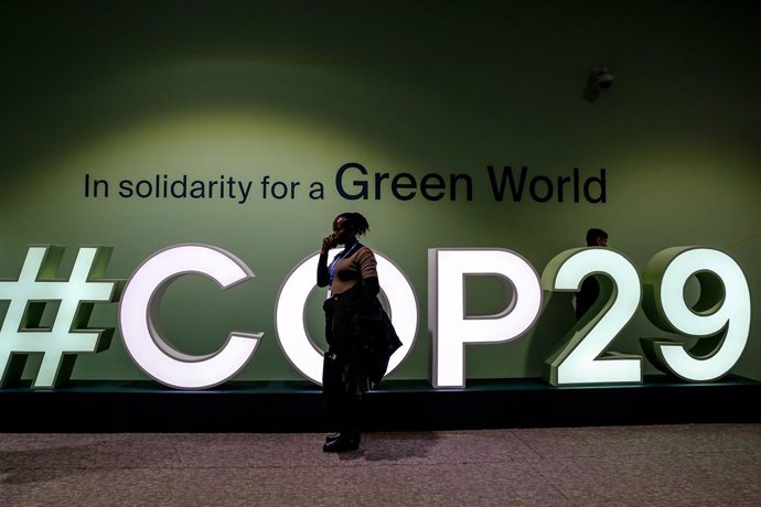 11 November 2024, Azerbaijan, Baku: A woman walks past a logo of COP29, UN Climate Change Conference, an event held by UNFCCC in Baku Olympic Stadium. Photo: Dominika Zarzycka/SOPA Images via ZUMA Press Wire/dpa