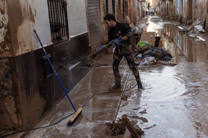 Diverses persones netegen el fang en el dia 13 després del pas de la DANA per Valencia