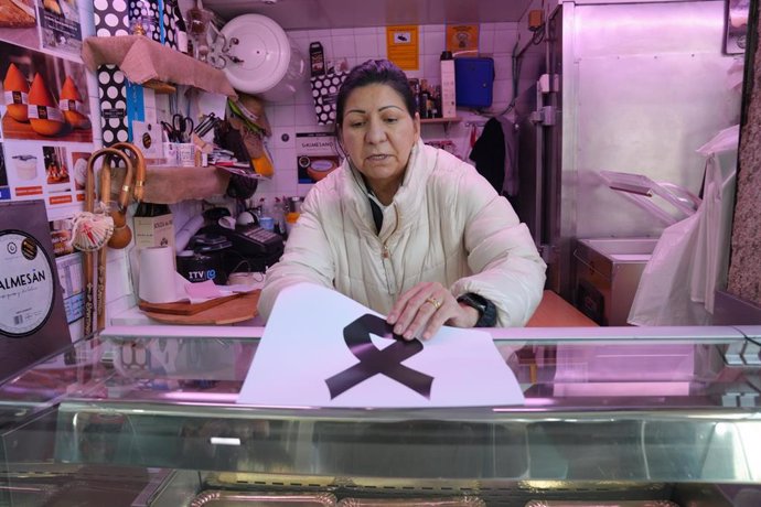 Una mujer coloca un crespón negro en una carnicería en la plaza de Abastos de Santiago, donde han matado al dueño de una carnicería, a 12 de noviembre de 2024, en Santiago de Compostela, A Coruña, Galicia (España). El propietario de la carnicería Chelo Mu