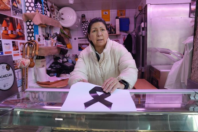 Una mujer coloca un crespón negro en una carnicería en la plaza de Abastos de Santiago, donde han matado al dueño de una carnicería, a 12 de noviembre de 2024, en Santiago de Compostela, A Coruña, Galicia (España). El propietario de la carnicería Chelo Mu