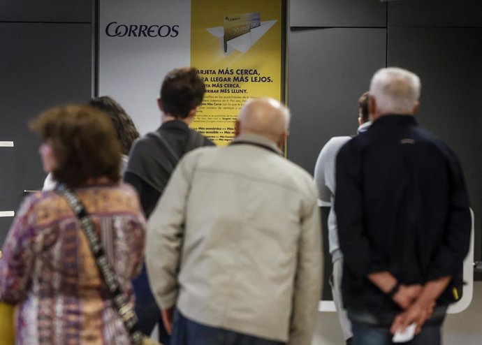 Archivo - Varias personas en una oficina de Correos