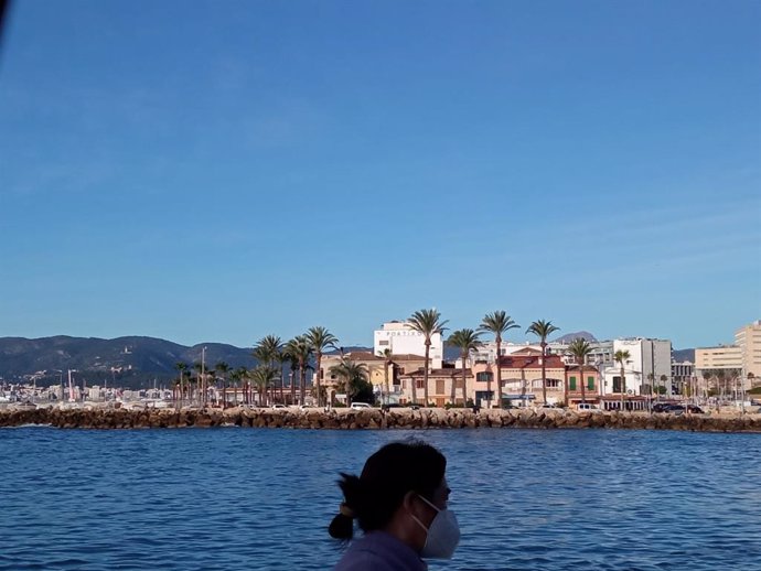 Archivo - Una mujer pasea con mascarilla en un día soleado de diciembre, en Palma.